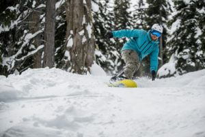 A snowboarder rides through the trees