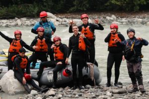 A group of people pose on a whitewater raft on the Elaho river