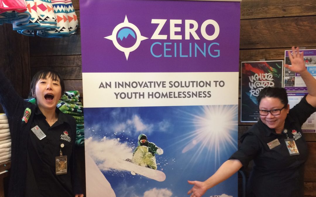 Two women pose next to a banner which says "Zero Ceiling: An innovative solution to youth homelessness"
