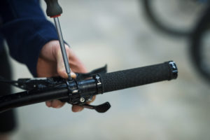 A person tightens the brakes on a mountain bike with a screwdriver. They work in a bike shop, thanks to funding from MEC.