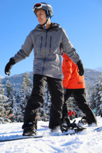 A photograph of a young man learning to snowboard for the first time