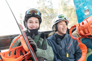 Close-up photograph of two young men in snowboard gear laughing
