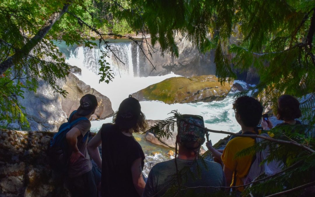 A few young people looking at a gorgeous waterfall and natural pool on one of Whistler's epic hikes. This summer we're adding hiking to our Adventure Sessions activities so we can help with social distancing.