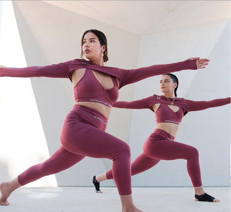 A photograph of two Indigenous young women practising yoga in the Matriarch Movement yoga kit