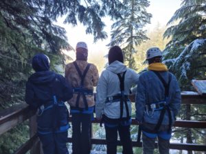 4 youth in our work 2 live program look over the edge of a mountain on a ziplining adventure.