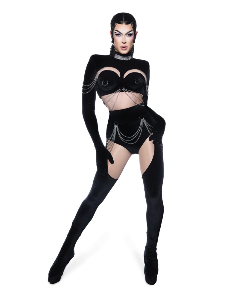 A photo of drag performer Gia Metric posing. She/they are wearing a skin tight black outfit and looking fierce
